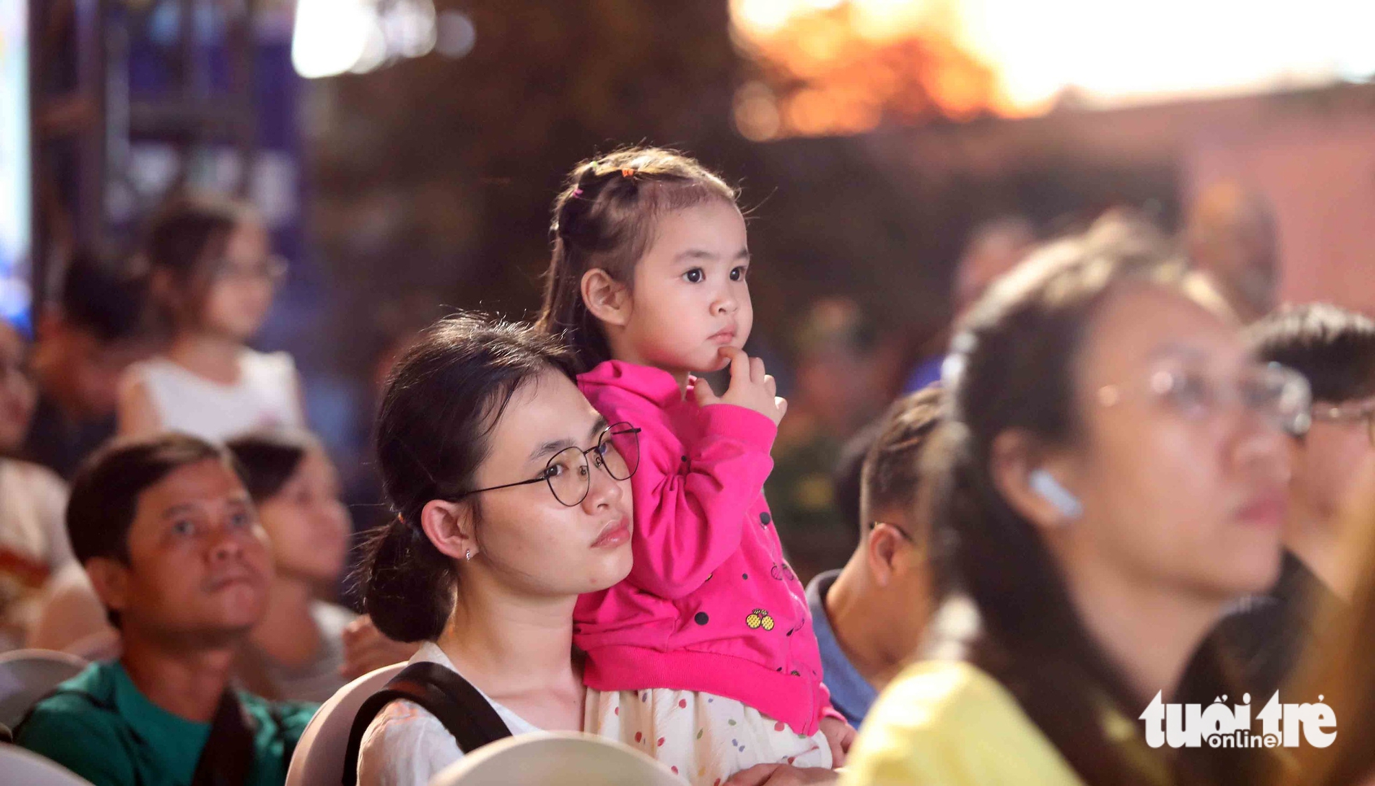 Em bé cùng mẹ chăm chú theo dõi biểu diễn võ thuật